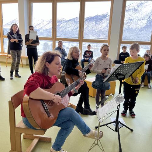 Musizierende Lehrerinnen und singende Kinder